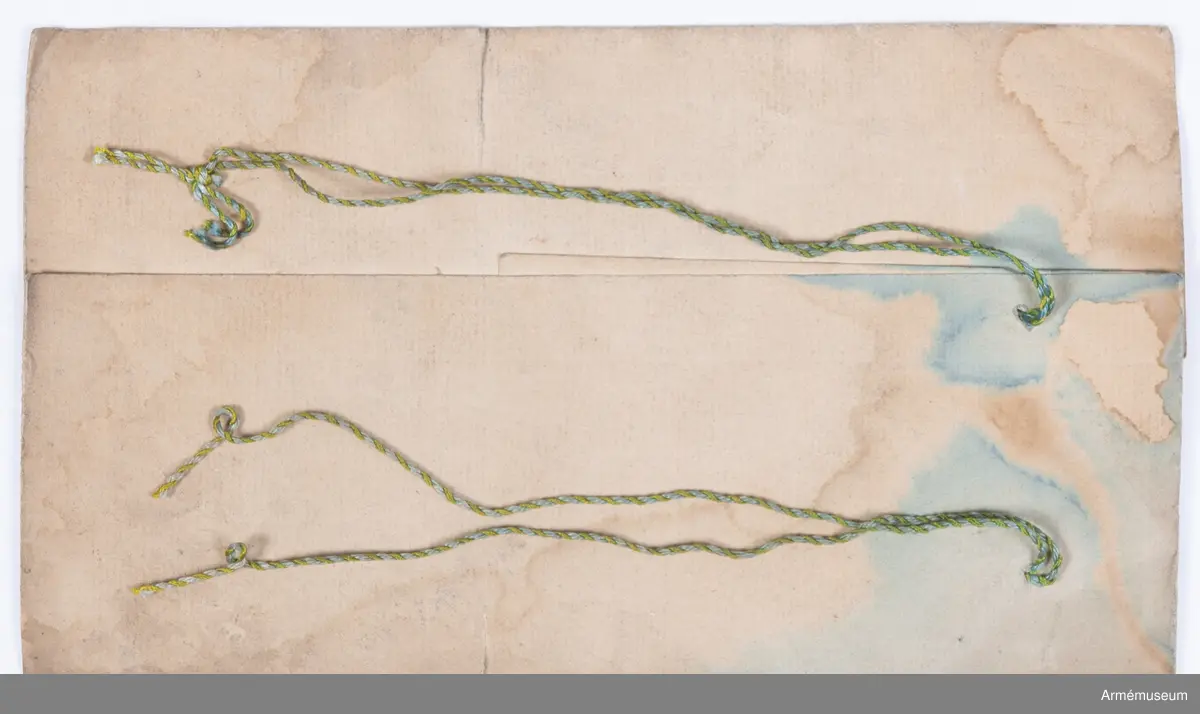 Två distinktionstecken av mässing i form av två korslagda yxor. Tecknen har 8 hål för fastsättning på uniformen.
Tecknen är fastsydda på fracken AM.015502:s ärmar.

Till distinktionstecknen hör en modelletikett med rött vaxsigill och följande text:
"Modell till Öfver-Timmermans distinction, att fästas på båda Jack ärmarne, Nådigast approberad under dena dag, Stockholms Slott d. 26 Aprill 1832, På nådigaste befallning M. Brahe, General Adjutant för Armén".
Sigillet pryds av Lilla Riksvapnet i mitten med följande text runt om: "Konungens Gen. Adjuts. Exprd. för Arméen".