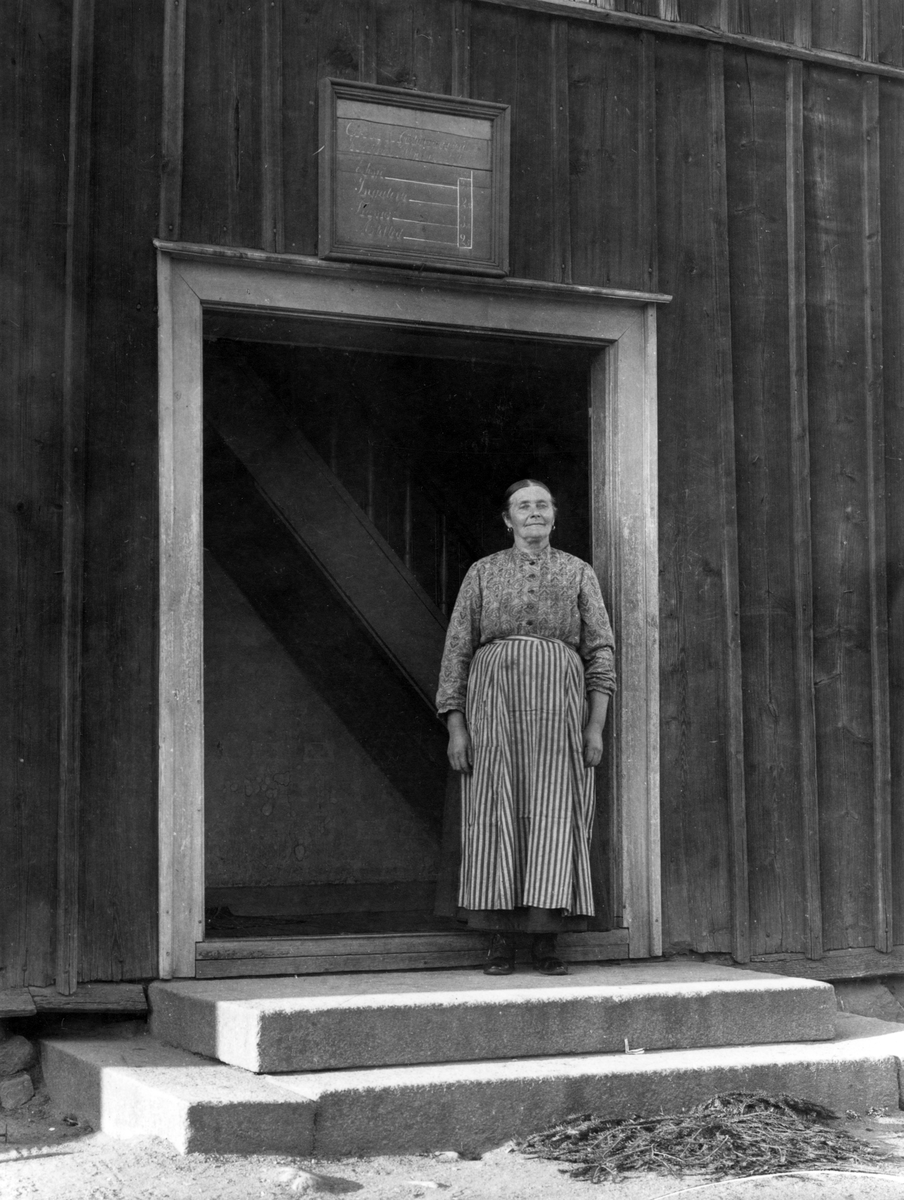 Gästgivaremor Hanna Elmberg välkomnar till värdshuset i Österby i Sund. Fotoåret 1914 var böndernas skjutstvång sedan länge upphävt men mat och husrum erbjöds ännu en tid. Upplysningsvis upphävdes skjutsstadgan i Sverige först 1933.