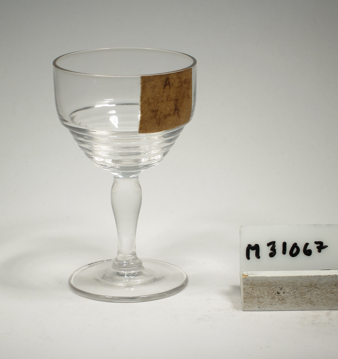 Formgivare: Ingrid Atterberg. Vinglas på ben och fot. Ovoid kupa med horisontella vulster på nedre delen. Pelarben.