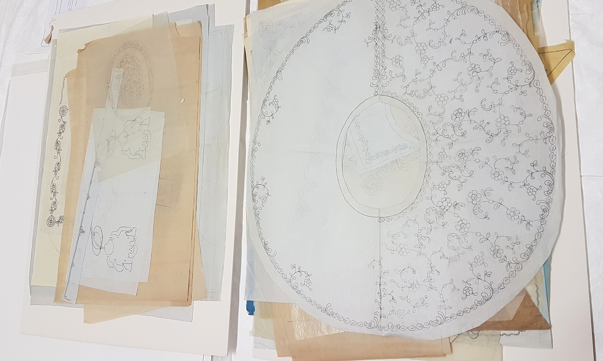Mapp innehållande många små och stora skisser för spets, de minsta ca 12X12 cm och de större ca 70X100 cm. 
De blå skisserna troligen utförda i tekniken cyanotype, övriga i blyerts eller tusch.