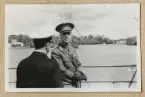 Bilden visar kronprins Gustav i samtal med en sjöofficerare ombord på Sverige. I bakgrunden syns övningsfartyget af Chapman med storflaggning.