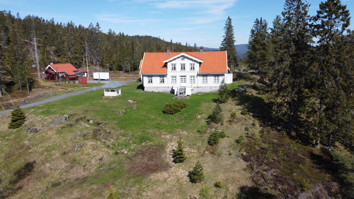 Laftet bygning i to etasjer med kjeller. Tegl på taket.