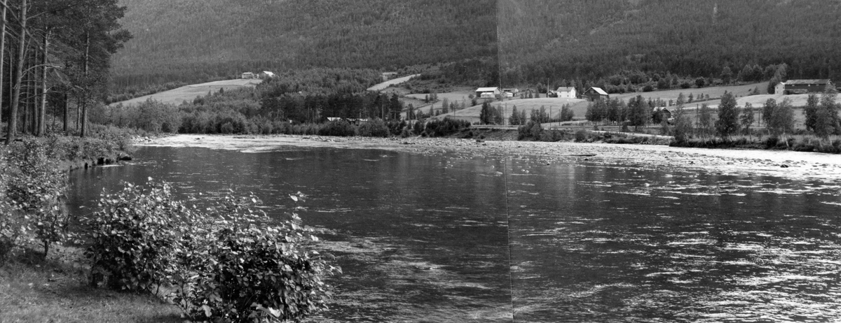 Elvelandskap ved Gudbrandsdalslågen på Brennhaug i den søndre delen av Dovre kommune i Oppland. Bildet er tatt fra østre elvebredd, der det vokste småkratt på elvebrinken og furuskog innenfor. Elveløpet var bredt og grunt, og tilsynelatende grunnest på midten, der det tilsynelatende var stein som brøt vannspeilet. Her hadde Glomma fellesfløtingsforening planer om å sette inn bulldoser som kunne skyve masse fra denne øra inn på elvebredden slik at fløtingstømmeret skulle kunne flyte uten å sette seg fast og pakke seg i hop i hauger. På motsatt side av elva – Baksida – lå det en del gardsbruk i slakt skrånende terreng. Bakenfor ser vi ei bratt, skogkledd li.