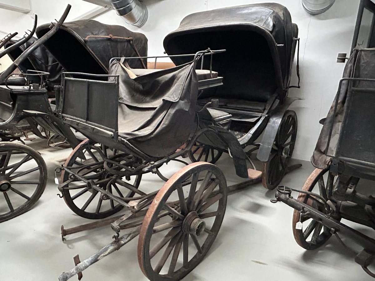 Svartmålad fyrhjulig hästvagn. Vagnen har öppen läderklädd kuskbock och sufflett över passagerarplatsen. Suffletten går att fälla bakåt vilket gör att hela vagnen är öppen. Svarta läderklädda säten för både framåt och bakåtresande. Fotsteg på varje sida. Stänkskydd för alla hjulen. Bakhjulen större än framhjulen.