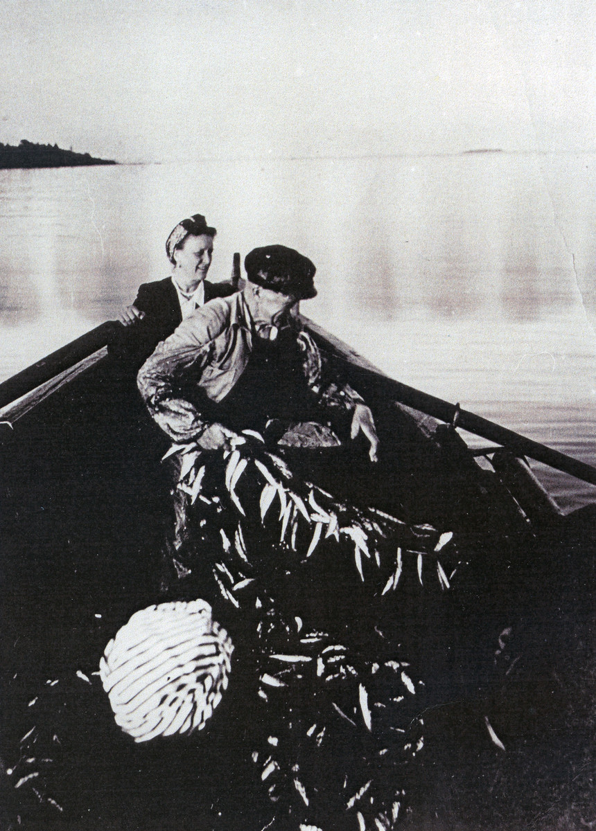 "Farbror Westergren" i en båt med strömmingssköten full, samt en kvinna som ror.