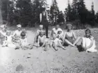 Många soldyrkande kvinnor, män och barn sittandes i sanden i Scoutviken, 1925.
