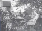 Män, kvinnor och barn som sitter till bords i arrendatorns berså, 1925.