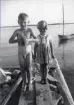 Stig och Siv på bryggan en sommardag med båt i bakgrunden, 1930-tal.