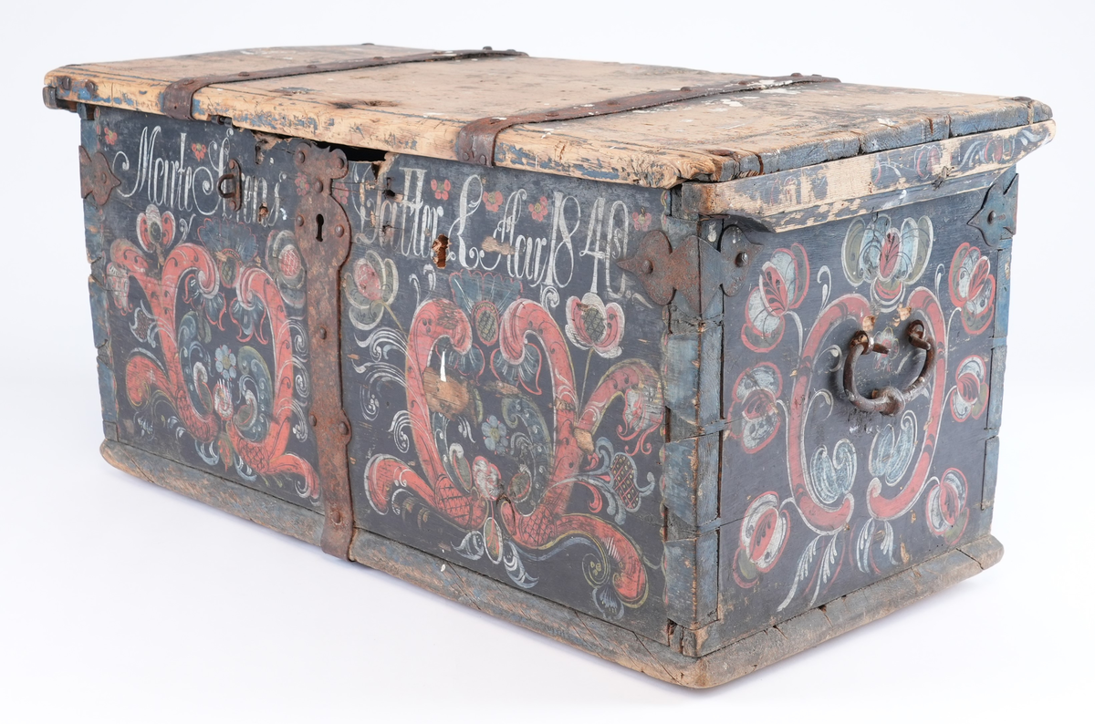 Kiste er rosemåla med alle kantar i blått og feltane mellom dei i svart. På begge sider av låsbeslaget på forsida måla symmetrisk dekorasjon. På svart bakgrunn raud rocaille (2 C-kurver mot kvarandre) med mange ulike blomstrar og blad som stikk ut av den. Blomstrane og blada måla i ulike fargar: kvit, gul, raud, blå, svart. På forsida over to rocaille inskripsjon måla i kvitt. Rocaille ornament gjentatt på de to kortsidene. Ornamenta liknar kvarandre som dannar ein homogen komposisjon, men kvert av dei er handmåla så de er forskjellige. På baksida berre svart bakgrunn og blå kantar.