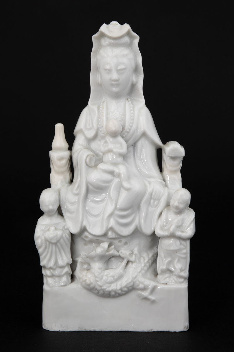 Figuren representerer den buddhistiske bodhisattavaen Guanyin, en barmhjertighetsgudinne. Hun er avbildet sittende med et barn i fanget. Barnet holder et ruyisepter. Guanyin er flankert av to figurer. Dette er hennes to akolytter, dragekongens datter Longnu, jadejomfuren, og Shoukai, det gylne barn. Disse to er i utgangspunktet taostiske figurer, og var assistentene til de åtte udødelige. Avbildet på denne måten er hun kjent som den "høyaktede hvitkledde." Ved basen under Guanyins føtter finner vi en drage. Guanyins posisjonering over en drage refererer til hennes stauts som Putuofjellets beskyttende bodhisattava og sørhavenes herskerinne og fiskernes beskytter.