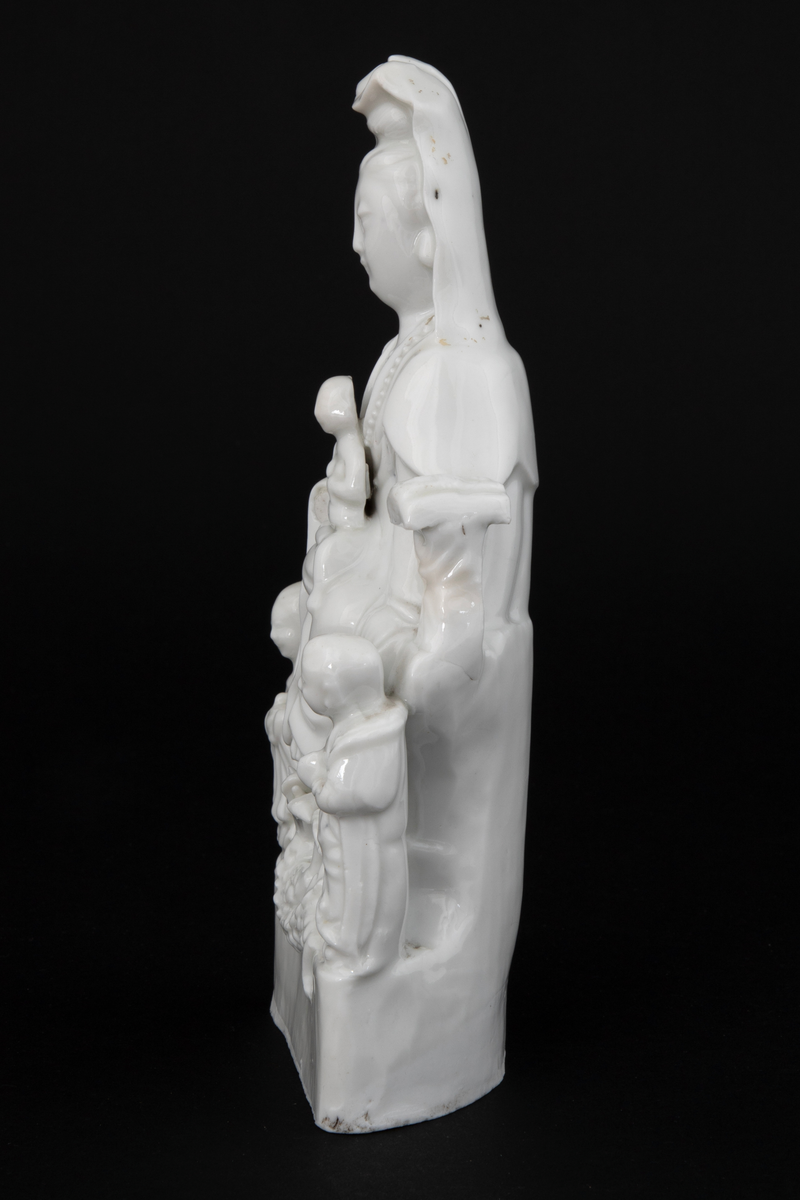 Figuren representerer den buddhistiske bodhisattavaen Guanyin, en barmhjertighetsgudinne. Hun er avbildet sittende med et barn i fanget. Barnet holder et ruyisepter. Guanyin er flankert av to figurer. Dette er hennes to akolytter, dragekongens datter Longnu, jadejomfuren, og Shoukai, det gylne barn. Disse to er i utgangspunktet taostiske figurer, og var assistentene til de åtte udødelige. Avbildet på denne måten er hun kjent som den "høyaktede hvitkledde." Ved basen under Guanyins føtter finner vi en drage. Guanyins posisjonering over en drage refererer til hennes stauts som Putuofjellets beskyttende bodhisattava og sørhavenes herskerinne og fiskernes beskytter.