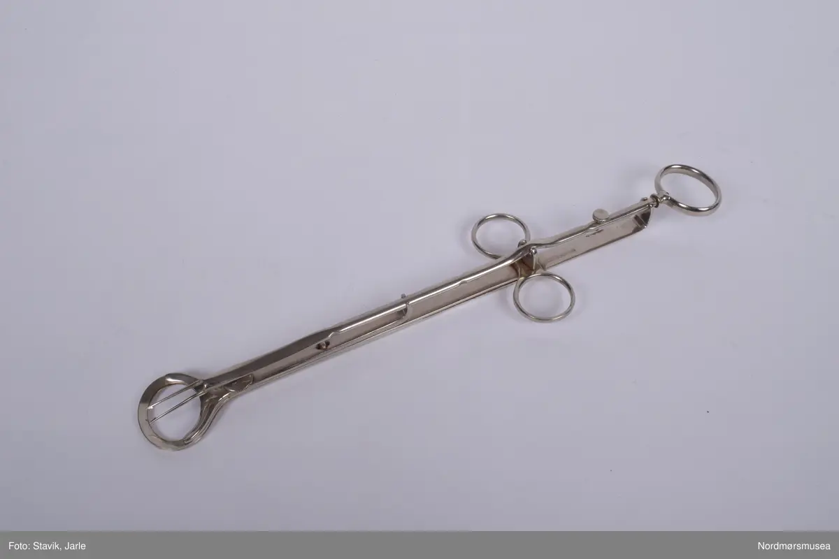 Instrument til tonsillectomi, fjerning av mandler.

To ovale flate flaskeåpnerlignende like deler er lagt opp hverandre med en del under bestående av to tynne spisser med mothaker. Bøyler til tre fingre, en på hver side og en på enden for å bevege disse delene. Bøylene i sammenslått tilstand legges oppå mandlene, deretter føres nålene med mothaker fram og inn i mandlene. De to flaskeåpnerlignende delene dras på fra hverandre og og mandlene kappes av mens de fortsatt sitter fast på nålene og kan nå fjernes.