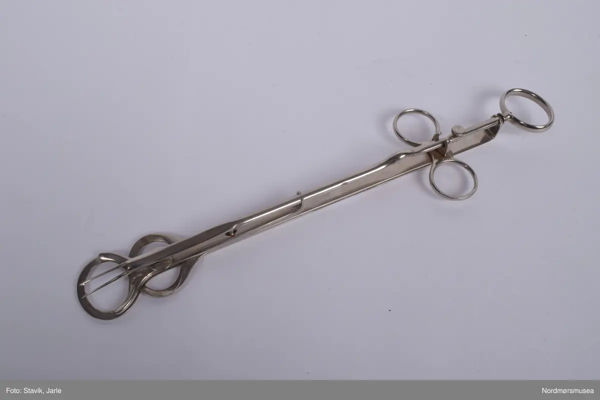 Instrument til tonsillectomi, fjerning av mandler.

To ovale flate flaskeåpnerlignende like deler er lagt opp hverandre med en del under bestående av to tynne spisser med mothaker. Bøyler til tre fingre, en på hver side og en på enden for å bevege disse delene. Bøylene i sammenslått tilstand legges oppå mandlene, deretter føres nålene med mothaker fram og inn i mandlene. De to flaskeåpnerlignende delene dras på fra hverandre og og mandlene kappes av mens de fortsatt sitter fast på nålene og kan nå fjernes.