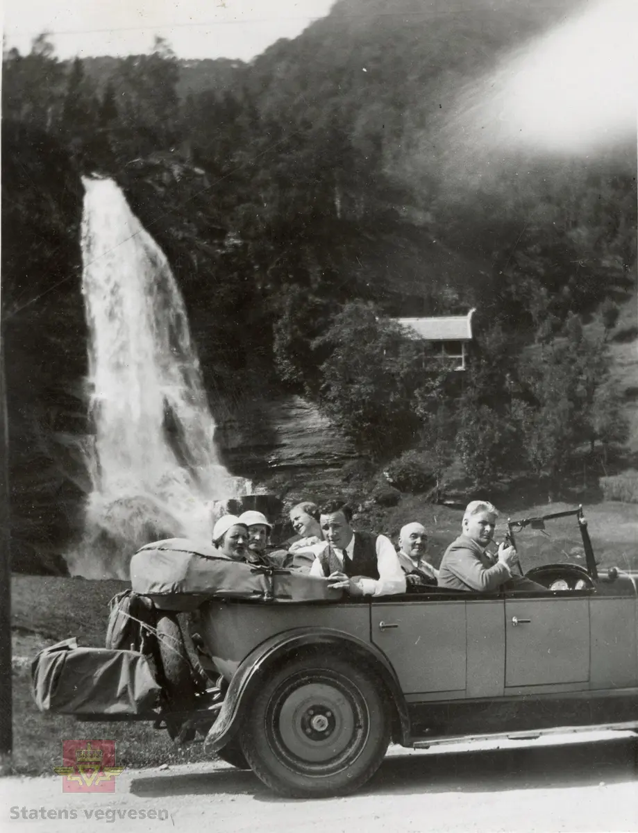 Bildet viser trolig Steindalsfossen i Hardanger ved Norheimsund. 
Bilbøkene 1928-1935 sier Ivar Frederiksen, Harstad, Nash personbil. (I 1935 titulert direktør).
American Car Spotter´s Guide 1920-39 viser at Nash 1927-28 hadde vinger på radiatorlokk, kunne leveres med platefelger og ellers var temmelig like. (Opplysninger fra Ivar Erlend Stav)