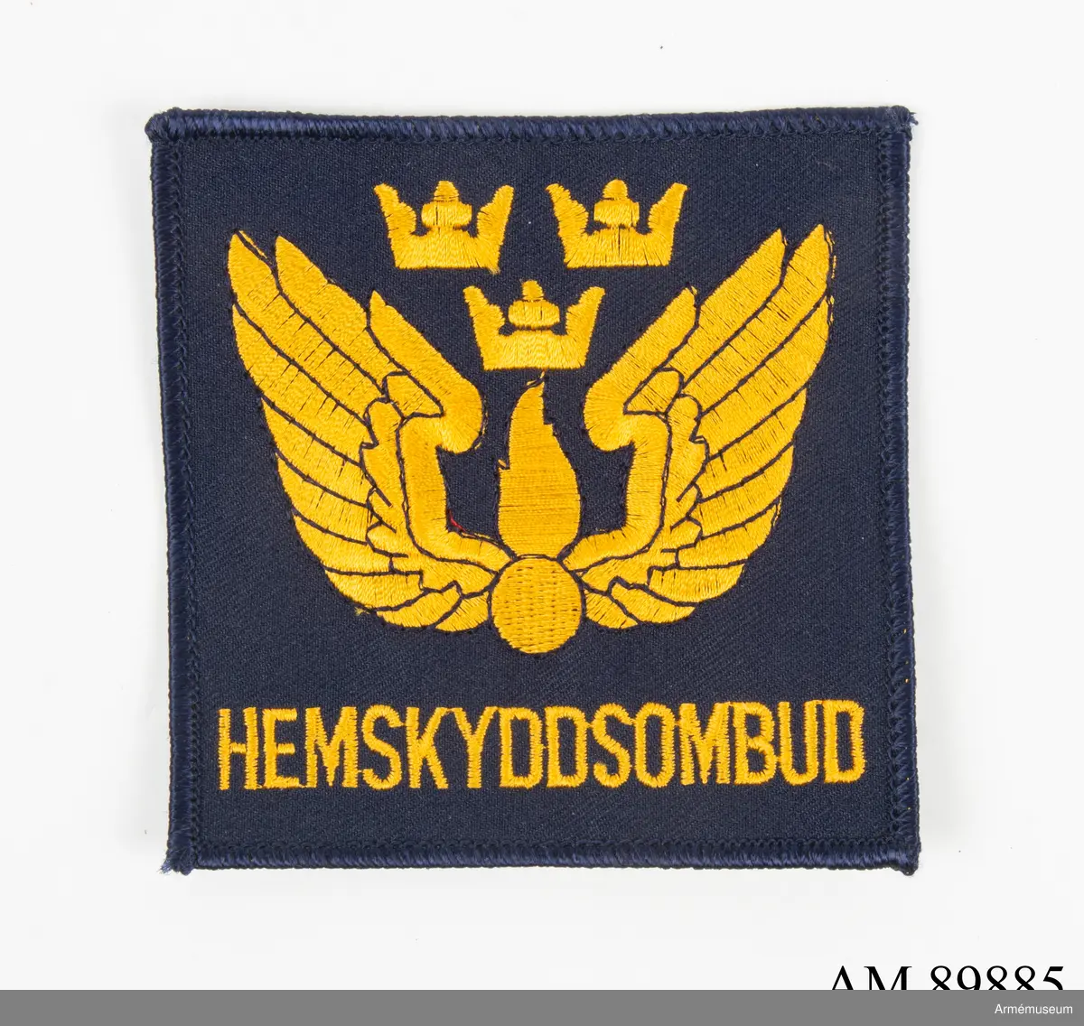 Märke med civilförsvarsförbundets symbol samt texten "Hemskyddsombud" mot en mörkblå bakgrund.
