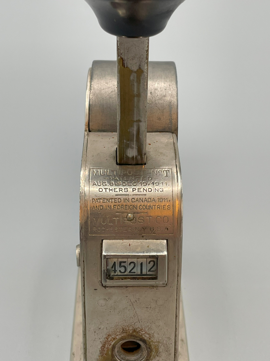 Frankeringsmaskin av amerikansk tillverkning, handtagsknopp av trä.

Multipost no T
Patented
Aug 8 and Dec 19 1911
Others pending
-----
Patented in Canada,
and in foreign countries
Multipost Co
