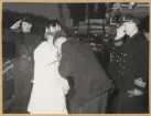 En sjöman kyssar handen på Göteborgs Lucia 1955. Två sjöofficerare hälsar kvinnorna välkommen ombord.
