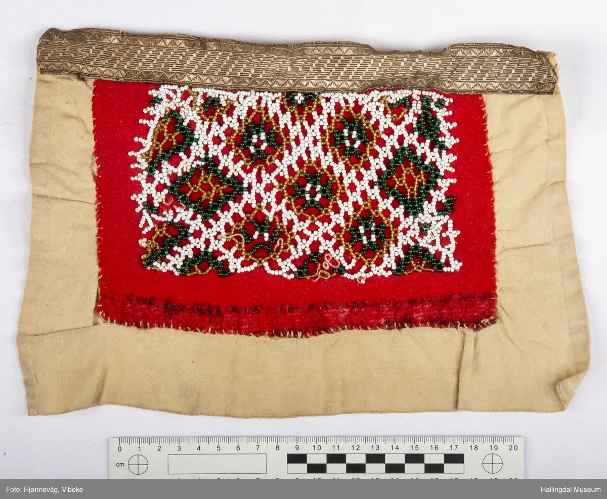 Håndsydd brystduk i lin, ull og silke med fløyelsband og glassperler i blomstermønster. Ubleika linlerret på baksida.
