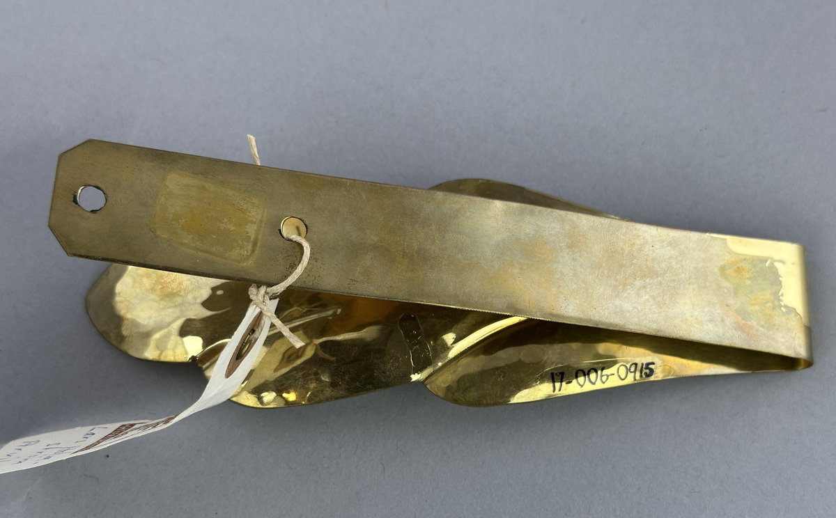 Gardinomtag av mässing med framsida i form av löv.