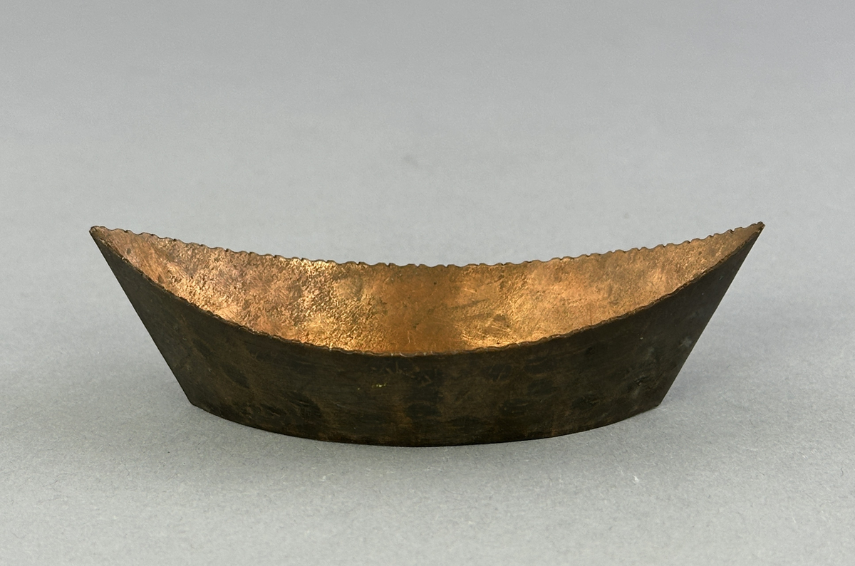 "Skål" av koppar, formad som en båt med mönster i botten.