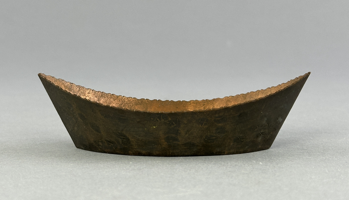 "Skål" av koppar, formad som en båt med mönster i botten.