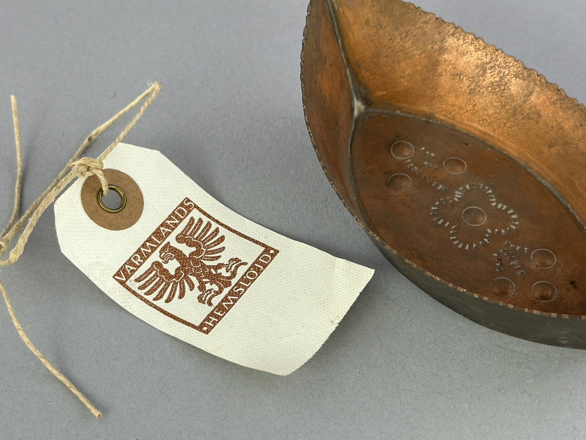 "Skål" av koppar, formad som en båt med mönster i botten.