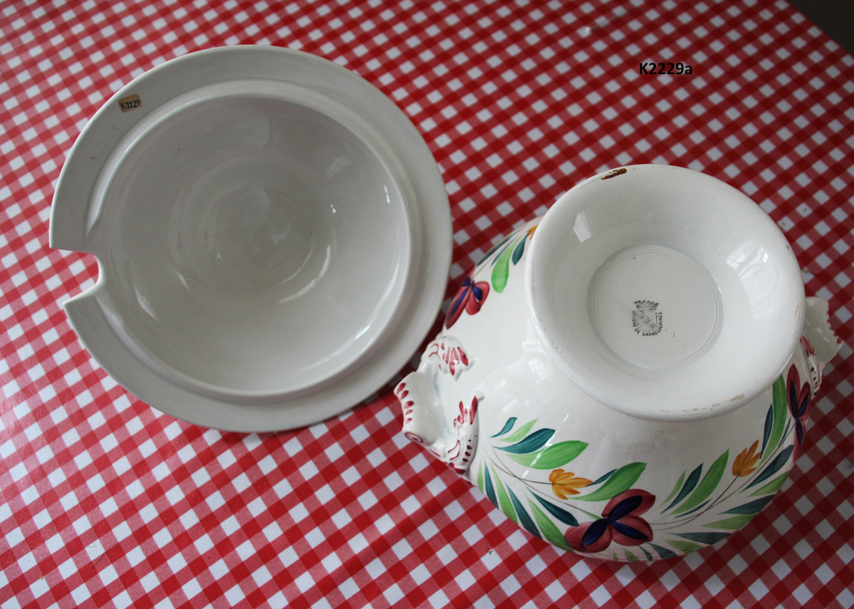 K 2229 
Servise, “Bondemønster”, Saarreguemines, 1900-åreme 
a) Terrin med lokk. 
Lokk. Hvelvet, bred bord langs kanten: grønn gren med røde og blå blomster, rund hankering med røde blad. 
b) Ovalt fat, med bord i brede strøk over bremmen. 
Stemplet i sort: Opaque de Saaregemines, H 169 A. 
c) Ovalt fat. Stemplet fabrikk merke og H 169 W. 
d) Ovalt fat. Stemplet i sort og i godset: 5 K. 
e) Båtformet skål (til pålegg). Avlang rned svakt svungne sider og konkavt buet i kortsidene. 
f) Make til e. 
g) Stettefat. 
h) Kopp. Vid rundsidet kopp, uten stett, forholdsvis lav. Stemplet i sort. 
i) Skål til koppen h).  Stemplet i sort. 
j) Kaffekanne, Pæreformet korpus, bølgende toppkontur, lang tut. Stemplet i sort og 169. Hvelvet lokk med rød toppfarge på lokkgrepet.
k) Fløtemugge, skrånende sider, riller oppe og nede , rillet hank, annerledes enn på den C-formede på kannen.
l) Sukkerkopp med lokk. Skrånende vegger, bredest nede, to hanker, riller oppe og nede, avtrappet lokk. Høyde med lokk 12,5. H. uten 7,2. Diam. bunn 10,8. 
m) Sausekopp. Eggformet skål med en skjellform i relieff , markert med rød farge, i den ene kortside, hvor hanken er. Smal liten skål med bred tut.
Fløtekopp og sukkerkopp av en annen design enn kanne, terrin og sausenebb, men samme mønster. Mønstret er det som kalles “Boerenbont” (broget bondemønster) og som ble laget først i Maastricht 
i Nederland, siden tatt opp av fabrikken Saarreguemirnes i Lorraine,og av Egersund Fayencefabrik i 1930-årene. 
n) Båtformet skål. Som e) Stemplet med sort. 
o) Ovalt fat. Stemplet Sarreguemines med sort og B 169. 
p) Terrin med lokk, stemplet med sort, og L i blindstempel.
Skrå fot, sterkt utskrånende sider, rundet av øverst, to sidehanker.
q) Underfat til terrin, rundt med to hanker. St. med sort og blindstempel: 3 R.
r) Potetfat. St. med sort og sort K.