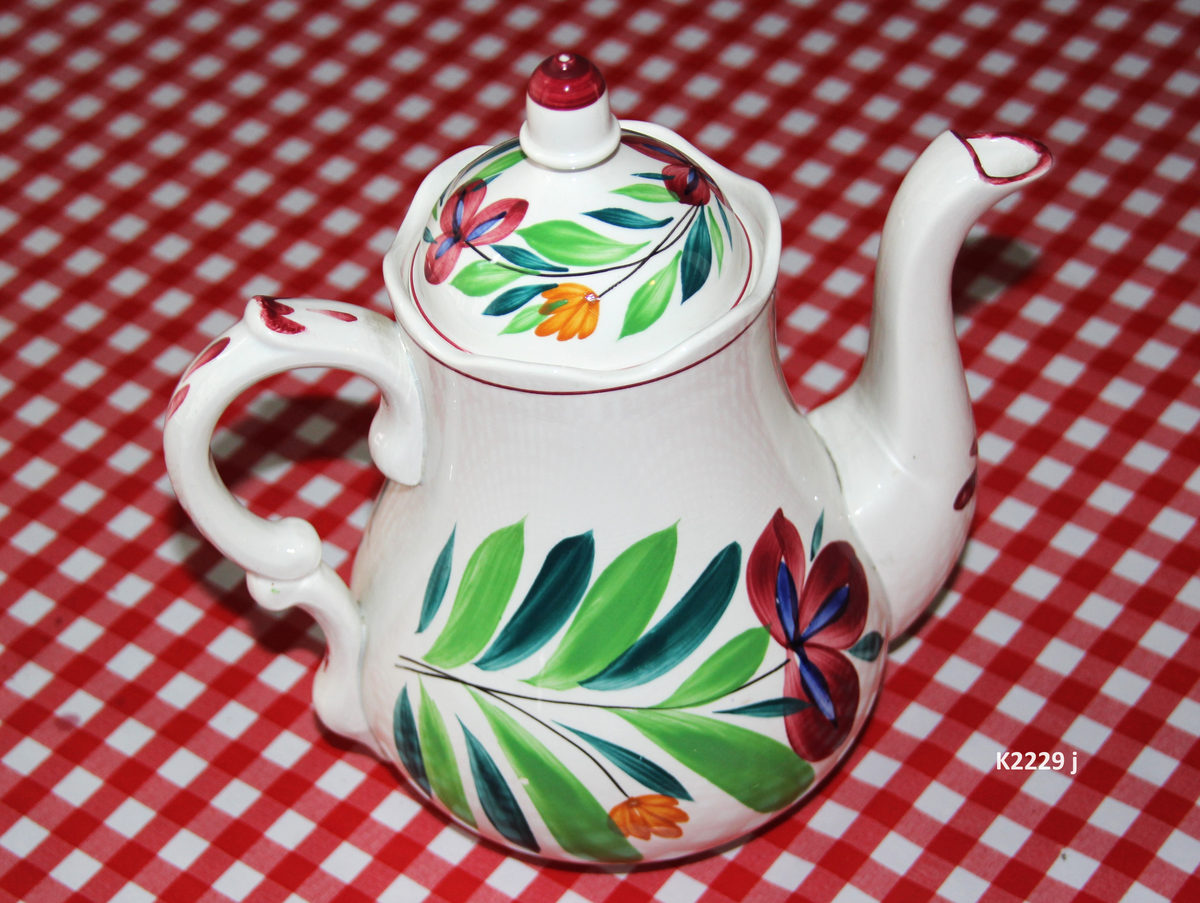 K 2229 
Servise, “Bondemønster”, Saarreguemines, 1900-åreme 
a) Terrin med lokk. 
Lokk. Hvelvet, bred bord langs kanten: grønn gren med røde og blå blomster, rund hankering med røde blad. 
b) Ovalt fat, med bord i brede strøk over bremmen. 
Stemplet i sort: Opaque de Saaregemines, H 169 A. 
c) Ovalt fat. Stemplet fabrikk merke og H 169 W. 
d) Ovalt fat. Stemplet i sort og i godset: 5 K. 
e) Båtformet skål (til pålegg). Avlang rned svakt svungne sider og konkavt buet i kortsidene. 
f) Make til e. 
g) Stettefat. 
h) Kopp. Vid rundsidet kopp, uten stett, forholdsvis lav. Stemplet i sort. 
i) Skål til koppen h).  Stemplet i sort. 
j) Kaffekanne, Pæreformet korpus, bølgende toppkontur, lang tut. Stemplet i sort og 169. Hvelvet lokk med rød toppfarge på lokkgrepet.
k) Fløtemugge, skrånende sider, riller oppe og nede , rillet hank, annerledes enn på den C-formede på kannen.
l) Sukkerkopp med lokk. Skrånende vegger, bredest nede, to hanker, riller oppe og nede, avtrappet lokk. Høyde med lokk 12,5. H. uten 7,2. Diam. bunn 10,8. 
m) Sausekopp. Eggformet skål med en skjellform i relieff , markert med rød farge, i den ene kortside, hvor hanken er. Smal liten skål med bred tut.
Fløtekopp og sukkerkopp av en annen design enn kanne, terrin og sausenebb, men samme mønster. Mønstret er det som kalles “Boerenbont” (broget bondemønster) og som ble laget først i Maastricht 
i Nederland, siden tatt opp av fabrikken Saarreguemirnes i Lorraine,og av Egersund Fayencefabrik i 1930-årene. 
n) Båtformet skål. Som e) Stemplet med sort. 
o) Ovalt fat. Stemplet Sarreguemines med sort og B 169. 
p) Terrin med lokk, stemplet med sort, og L i blindstempel.
Skrå fot, sterkt utskrånende sider, rundet av øverst, to sidehanker.
q) Underfat til terrin, rundt med to hanker. St. med sort og blindstempel: 3 R.
r) Potetfat. St. med sort og sort K.
