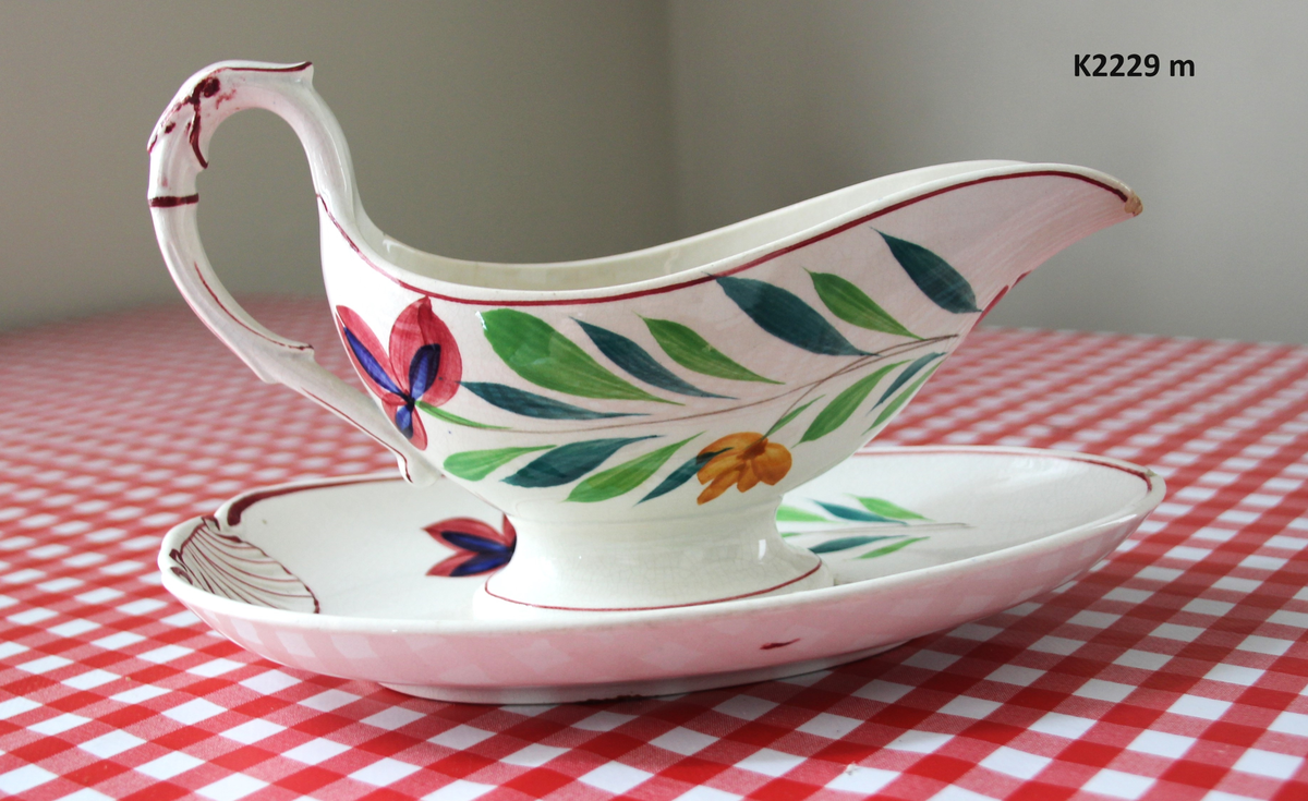 K 2229 
Servise, “Bondemønster”, Saarreguemines, 1900-åreme 
a) Terrin med lokk. 
Lokk. Hvelvet, bred bord langs kanten: grønn gren med røde og blå blomster, rund hankering med røde blad. 
b) Ovalt fat, med bord i brede strøk over bremmen. 
Stemplet i sort: Opaque de Saaregemines, H 169 A. 
c) Ovalt fat. Stemplet fabrikk merke og H 169 W. 
d) Ovalt fat. Stemplet i sort og i godset: 5 K. 
e) Båtformet skål (til pålegg). Avlang rned svakt svungne sider og konkavt buet i kortsidene. 
f) Make til e. 
g) Stettefat. 
h) Kopp. Vid rundsidet kopp, uten stett, forholdsvis lav. Stemplet i sort. 
i) Skål til koppen h).  Stemplet i sort. 
j) Kaffekanne, Pæreformet korpus, bølgende toppkontur, lang tut. Stemplet i sort og 169. Hvelvet lokk med rød toppfarge på lokkgrepet.
k) Fløtemugge, skrånende sider, riller oppe og nede , rillet hank, annerledes enn på den C-formede på kannen.
l) Sukkerkopp med lokk. Skrånende vegger, bredest nede, to hanker, riller oppe og nede, avtrappet lokk. Høyde med lokk 12,5. H. uten 7,2. Diam. bunn 10,8. 
m) Sausekopp. Eggformet skål med en skjellform i relieff , markert med rød farge, i den ene kortside, hvor hanken er. Smal liten skål med bred tut.
Fløtekopp og sukkerkopp av en annen design enn kanne, terrin og sausenebb, men samme mønster. Mønstret er det som kalles “Boerenbont” (broget bondemønster) og som ble laget først i Maastricht 
i Nederland, siden tatt opp av fabrikken Saarreguemirnes i Lorraine,og av Egersund Fayencefabrik i 1930-årene. 
n) Båtformet skål. Som e) Stemplet med sort. 
o) Ovalt fat. Stemplet Sarreguemines med sort og B 169. 
p) Terrin med lokk, stemplet med sort, og L i blindstempel.
Skrå fot, sterkt utskrånende sider, rundet av øverst, to sidehanker.
q) Underfat til terrin, rundt med to hanker. St. med sort og blindstempel: 3 R.
r) Potetfat. St. med sort og sort K.