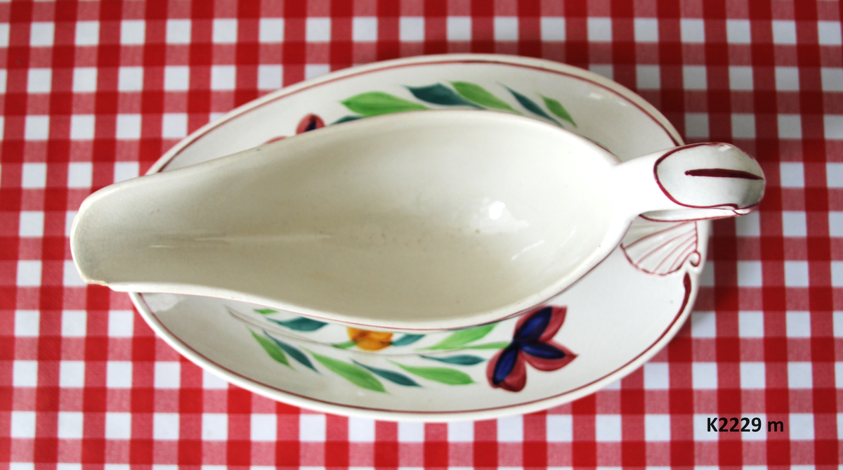 K 2229 
Servise, “Bondemønster”, Saarreguemines, 1900-åreme 
a) Terrin med lokk. 
Lokk. Hvelvet, bred bord langs kanten: grønn gren med røde og blå blomster, rund hankering med røde blad. 
b) Ovalt fat, med bord i brede strøk over bremmen. 
Stemplet i sort: Opaque de Saaregemines, H 169 A. 
c) Ovalt fat. Stemplet fabrikk merke og H 169 W. 
d) Ovalt fat. Stemplet i sort og i godset: 5 K. 
e) Båtformet skål (til pålegg). Avlang rned svakt svungne sider og konkavt buet i kortsidene. 
f) Make til e. 
g) Stettefat. 
h) Kopp. Vid rundsidet kopp, uten stett, forholdsvis lav. Stemplet i sort. 
i) Skål til koppen h).  Stemplet i sort. 
j) Kaffekanne, Pæreformet korpus, bølgende toppkontur, lang tut. Stemplet i sort og 169. Hvelvet lokk med rød toppfarge på lokkgrepet.
k) Fløtemugge, skrånende sider, riller oppe og nede , rillet hank, annerledes enn på den C-formede på kannen.
l) Sukkerkopp med lokk. Skrånende vegger, bredest nede, to hanker, riller oppe og nede, avtrappet lokk. Høyde med lokk 12,5. H. uten 7,2. Diam. bunn 10,8. 
m) Sausekopp. Eggformet skål med en skjellform i relieff , markert med rød farge, i den ene kortside, hvor hanken er. Smal liten skål med bred tut.
Fløtekopp og sukkerkopp av en annen design enn kanne, terrin og sausenebb, men samme mønster. Mønstret er det som kalles “Boerenbont” (broget bondemønster) og som ble laget først i Maastricht 
i Nederland, siden tatt opp av fabrikken Saarreguemirnes i Lorraine,og av Egersund Fayencefabrik i 1930-årene. 
n) Båtformet skål. Som e) Stemplet med sort. 
o) Ovalt fat. Stemplet Sarreguemines med sort og B 169. 
p) Terrin med lokk, stemplet med sort, og L i blindstempel.
Skrå fot, sterkt utskrånende sider, rundet av øverst, to sidehanker.
q) Underfat til terrin, rundt med to hanker. St. med sort og blindstempel: 3 R.
r) Potetfat. St. med sort og sort K.