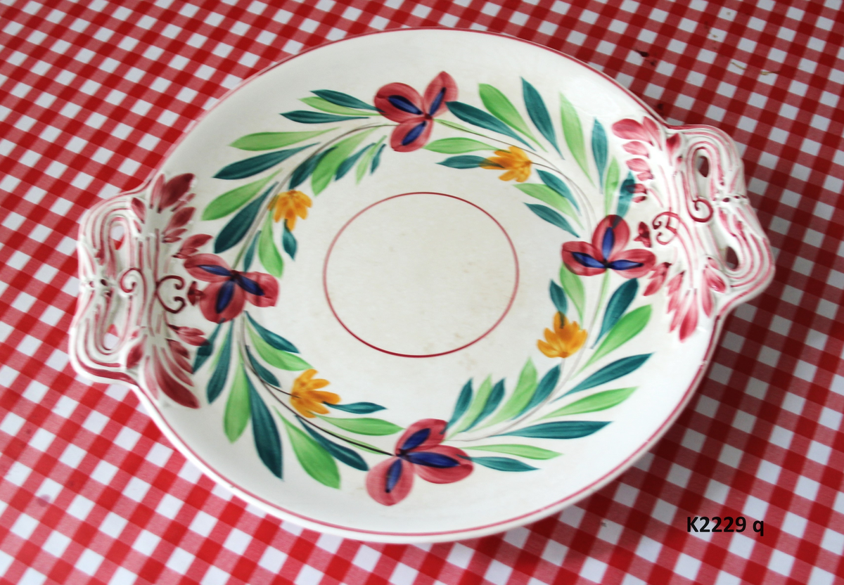 K 2229 
Servise, “Bondemønster”, Saarreguemines, 1900-åreme 
a) Terrin med lokk. 
Lokk. Hvelvet, bred bord langs kanten: grønn gren med røde og blå blomster, rund hankering med røde blad. 
b) Ovalt fat, med bord i brede strøk over bremmen. 
Stemplet i sort: Opaque de Saaregemines, H 169 A. 
c) Ovalt fat. Stemplet fabrikk merke og H 169 W. 
d) Ovalt fat. Stemplet i sort og i godset: 5 K. 
e) Båtformet skål (til pålegg). Avlang rned svakt svungne sider og konkavt buet i kortsidene. 
f) Make til e. 
g) Stettefat. 
h) Kopp. Vid rundsidet kopp, uten stett, forholdsvis lav. Stemplet i sort. 
i) Skål til koppen h).  Stemplet i sort. 
j) Kaffekanne, Pæreformet korpus, bølgende toppkontur, lang tut. Stemplet i sort og 169. Hvelvet lokk med rød toppfarge på lokkgrepet.
k) Fløtemugge, skrånende sider, riller oppe og nede , rillet hank, annerledes enn på den C-formede på kannen.
l) Sukkerkopp med lokk. Skrånende vegger, bredest nede, to hanker, riller oppe og nede, avtrappet lokk. Høyde med lokk 12,5. H. uten 7,2. Diam. bunn 10,8. 
m) Sausekopp. Eggformet skål med en skjellform i relieff , markert med rød farge, i den ene kortside, hvor hanken er. Smal liten skål med bred tut.
Fløtekopp og sukkerkopp av en annen design enn kanne, terrin og sausenebb, men samme mønster. Mønstret er det som kalles “Boerenbont” (broget bondemønster) og som ble laget først i Maastricht 
i Nederland, siden tatt opp av fabrikken Saarreguemirnes i Lorraine,og av Egersund Fayencefabrik i 1930-årene. 
n) Båtformet skål. Som e) Stemplet med sort. 
o) Ovalt fat. Stemplet Sarreguemines med sort og B 169. 
p) Terrin med lokk, stemplet med sort, og L i blindstempel.
Skrå fot, sterkt utskrånende sider, rundet av øverst, to sidehanker.
q) Underfat til terrin, rundt med to hanker. St. med sort og blindstempel: 3 R.
r) Potetfat. St. med sort og sort K.