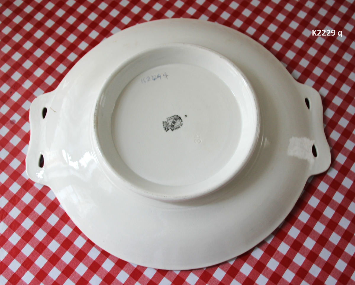 K 2229 
Servise, “Bondemønster”, Saarreguemines, 1900-åreme 
a) Terrin med lokk. 
Lokk. Hvelvet, bred bord langs kanten: grønn gren med røde og blå blomster, rund hankering med røde blad. 
b) Ovalt fat, med bord i brede strøk over bremmen. 
Stemplet i sort: Opaque de Saaregemines, H 169 A. 
c) Ovalt fat. Stemplet fabrikk merke og H 169 W. 
d) Ovalt fat. Stemplet i sort og i godset: 5 K. 
e) Båtformet skål (til pålegg). Avlang rned svakt svungne sider og konkavt buet i kortsidene. 
f) Make til e. 
g) Stettefat. 
h) Kopp. Vid rundsidet kopp, uten stett, forholdsvis lav. Stemplet i sort. 
i) Skål til koppen h).  Stemplet i sort. 
j) Kaffekanne, Pæreformet korpus, bølgende toppkontur, lang tut. Stemplet i sort og 169. Hvelvet lokk med rød toppfarge på lokkgrepet.
k) Fløtemugge, skrånende sider, riller oppe og nede , rillet hank, annerledes enn på den C-formede på kannen.
l) Sukkerkopp med lokk. Skrånende vegger, bredest nede, to hanker, riller oppe og nede, avtrappet lokk. Høyde med lokk 12,5. H. uten 7,2. Diam. bunn 10,8. 
m) Sausekopp. Eggformet skål med en skjellform i relieff , markert med rød farge, i den ene kortside, hvor hanken er. Smal liten skål med bred tut.
Fløtekopp og sukkerkopp av en annen design enn kanne, terrin og sausenebb, men samme mønster. Mønstret er det som kalles “Boerenbont” (broget bondemønster) og som ble laget først i Maastricht 
i Nederland, siden tatt opp av fabrikken Saarreguemirnes i Lorraine,og av Egersund Fayencefabrik i 1930-årene. 
n) Båtformet skål. Som e) Stemplet med sort. 
o) Ovalt fat. Stemplet Sarreguemines med sort og B 169. 
p) Terrin med lokk, stemplet med sort, og L i blindstempel.
Skrå fot, sterkt utskrånende sider, rundet av øverst, to sidehanker.
q) Underfat til terrin, rundt med to hanker. St. med sort og blindstempel: 3 R.
r) Potetfat. St. med sort og sort K.
