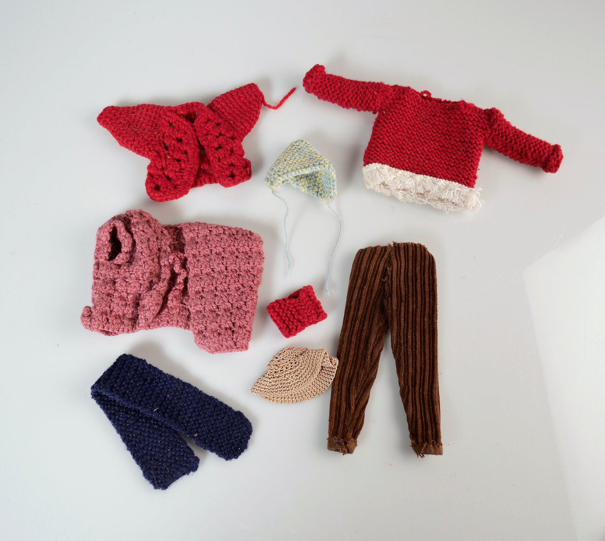 Barbiedocka med ljust hår. Rosarutig klänning med broderade blommor på vit krage. Rosa skärp och rosa klackskor. Till dockan har givaren och hennes mamma gjort egna kläder.

1a: Barbiedocka
1b: Klänning
1c: Skärp
1d-e: Skor

Dräktdelar till barbie. Hemgjorda av givaren eller hennes mamma. 
2ab: Orange dräkt bestående av tröja och kjol. 
3a-d: Virkad gul dräkt bestående av jacka, kjol, väska och hatt.
4: Virkad röd jacka. 
5: Virkad rosa jacka. 
6: Bruna manchesterbyxor. 
7: Blå halsduk
8: Beige hatt 
9: Röd tröja med vit kant. 
10: Röd mössa/halsduk
11: Blågul mössa 
12: Vit brudklänning
13: Blå klänning med vit spets.