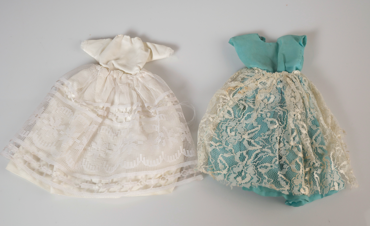 Barbiedocka med ljust hår. Rosarutig klänning med broderade blommor på vit krage. Rosa skärp och rosa klackskor. Till dockan har givaren och hennes mamma gjort egna kläder.

1a: Barbiedocka
1b: Klänning
1c: Skärp
1d-e: Skor

Dräktdelar till barbie. Hemgjorda av givaren eller hennes mamma. 
2ab: Orange dräkt bestående av tröja och kjol. 
3a-d: Virkad gul dräkt bestående av jacka, kjol, väska och hatt.
4: Virkad röd jacka. 
5: Virkad rosa jacka. 
6: Bruna manchesterbyxor. 
7: Blå halsduk
8: Beige hatt 
9: Röd tröja med vit kant. 
10: Röd mössa/halsduk
11: Blågul mössa 
12: Vit brudklänning
13: Blå klänning med vit spets.
