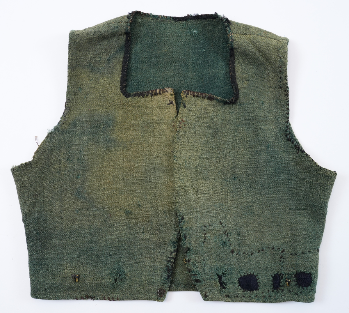 Livstykke som er overdel til kvinnedrakt. Livstykke i grønn ull med firskoren halsopning. Skal festast heilt ihop framme med 11 sett hekter og hemper. Hekter og hemper rundt livet til feste for skjørt. Rundt ermeopningane har det vore enkel fald, seinare er dette stadvis forsterka med overkast av grov tråd. Det same er tilfellet rundt halsopningen der det opphavleg har vore svart ullband. Livstykket er reparert med svarte og blå bøter i nedkant. Framkanten på livet er runda for å lage plass til bysten.