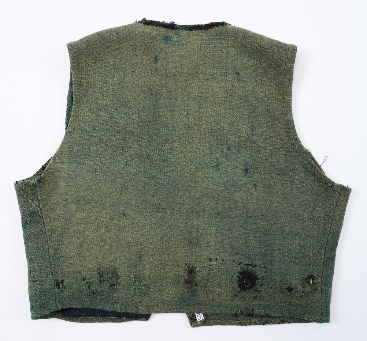 Livstykke som er overdel til kvinnedrakt. Livstykke i grønn ull med firskoren halsopning. Skal festast heilt ihop framme med 11 sett hekter og hemper. Hekter og hemper rundt livet til feste for skjørt. Rundt ermeopningane har det vore enkel fald, seinare er dette stadvis forsterka med overkast av grov tråd. Det same er tilfellet rundt halsopningen der det opphavleg har vore svart ullband. Livstykket er reparert med svarte og blå bøter i nedkant. Framkanten på livet er runda for å lage plass til bysten.