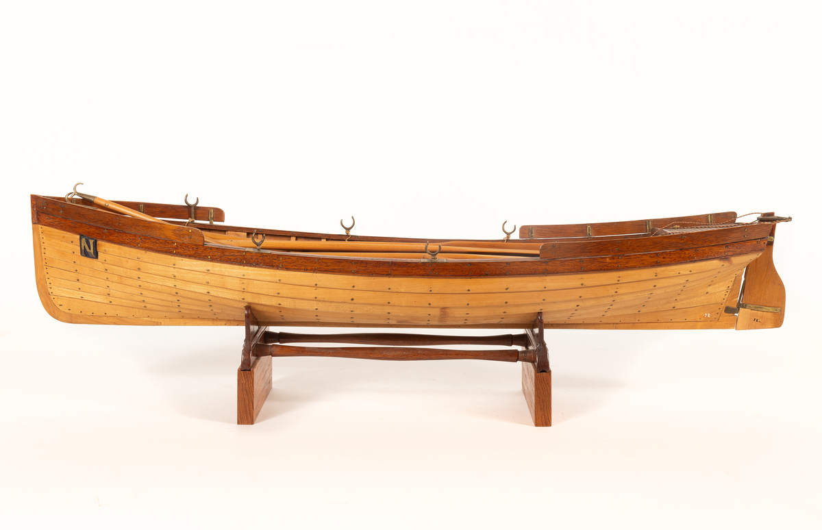 Gigg av 1834 års typ för korvetten Najaden. Bordlagd på spant, klink av bok, med fullständig inredning. 5 årtullar , 5 stycken åror, 1 mast, 2 båtshakar, 1 spri, 1 öskar. Roder med metallskädda. Skvättbord, trall och bänkar av mahogny.
Tillhört modellen "den gamla korvetten Najaden"