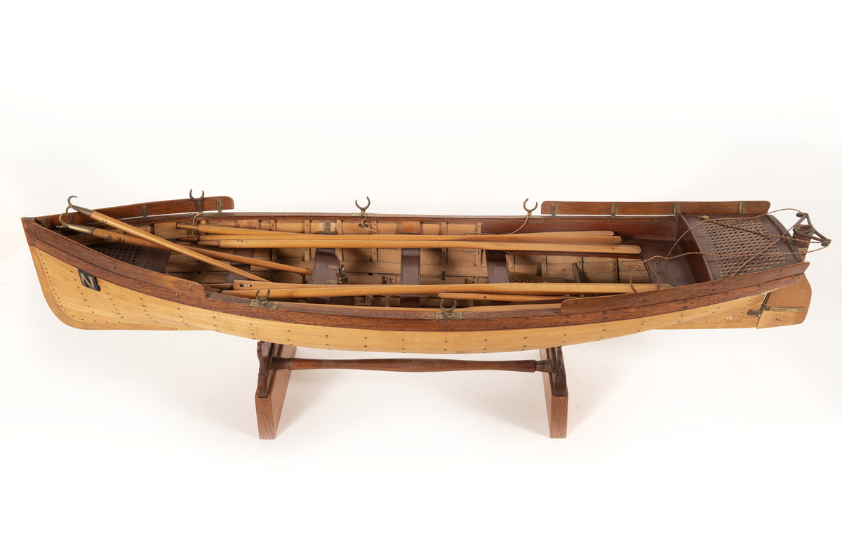 Gigg av 1834 års typ för korvetten Najaden. Bordlagd på spant, klink av bok, med fullständig inredning. 5 årtullar , 5 stycken åror, 1 mast, 2 båtshakar, 1 spri, 1 öskar. Roder med metallskädda. Skvättbord, trall och bänkar av mahogny.
Tillhört modellen "den gamla korvetten Najaden"