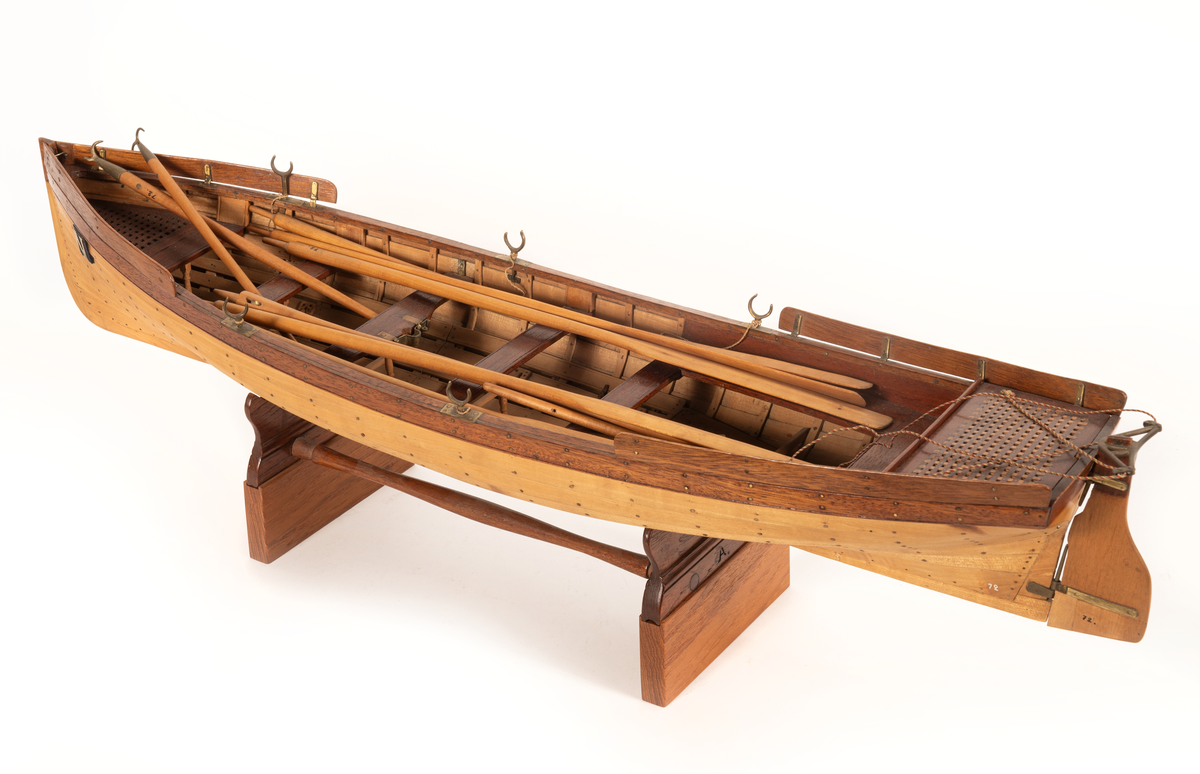 Gigg av 1834 års typ för korvetten Najaden. Bordlagd på spant, klink av bok, med fullständig inredning. 5 årtullar , 5 stycken åror, 1 mast, 2 båtshakar, 1 spri, 1 öskar. Roder med metallskädda. Skvättbord, trall och bänkar av mahogny.
Tillhört modellen "den gamla korvetten Najaden"