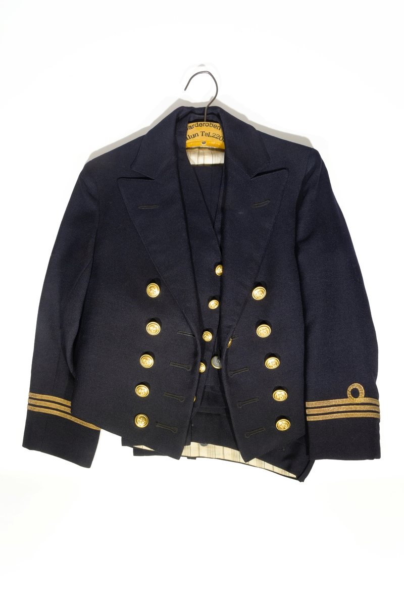 Uniformsjacka (marinen) till barn i mörkblått ylletyg. Försedd med fem rader av guldfärgade knappar med motiv av ankare. Ärmarna pryds av tre rader med guldfärgat band. Jackan är fodrar med ett svart tyg och ett randigt tyg med blå och bruna ränder på oblekt bas på ärmarnas insida. Jackan har en inneficka på höger sida. I jackans nackstycke finns en etikett med texten "Barngarderoben Falun" samt en hängare. 