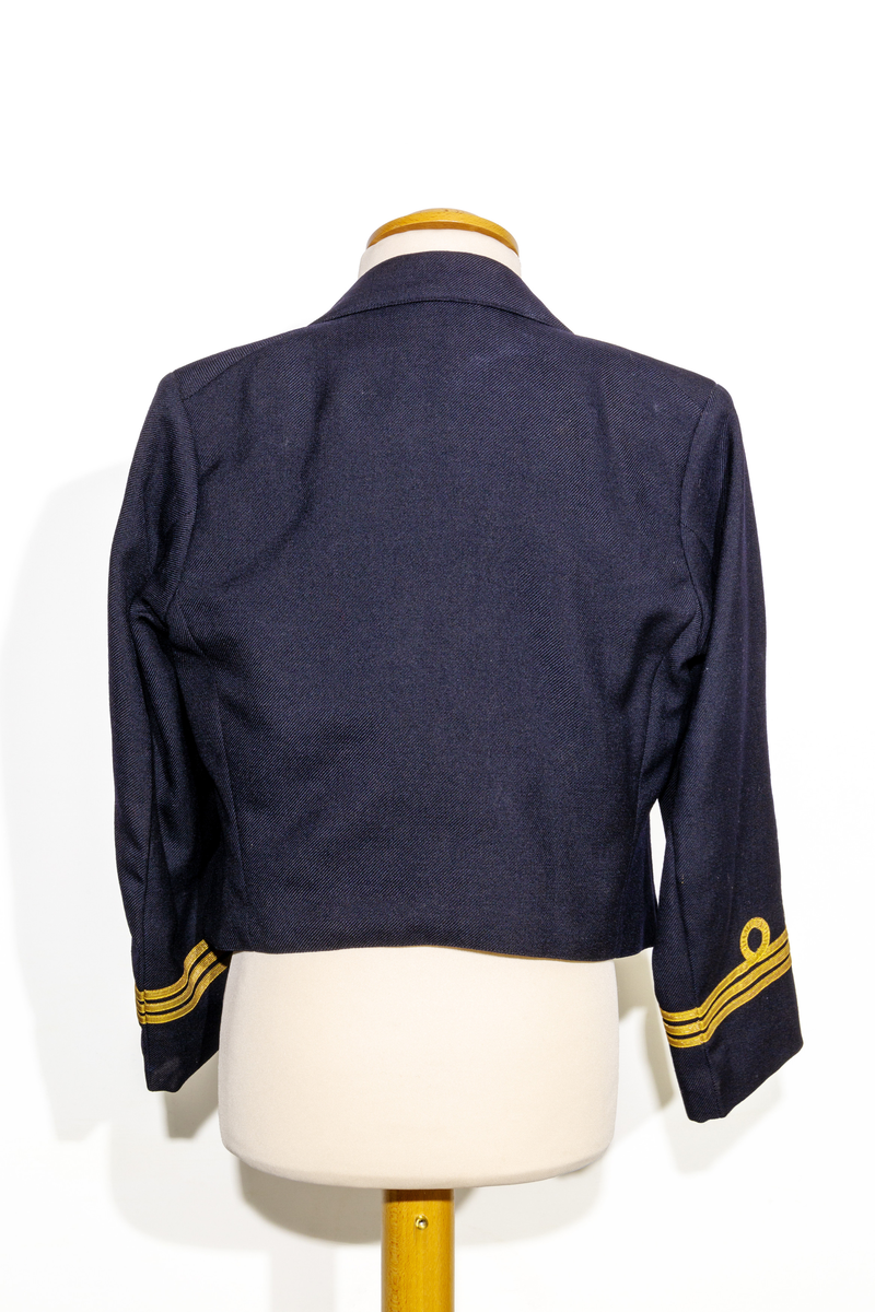 Uniformsjacka (marinen) till barn i mörkblått ylletyg. Försedd med fem rader av guldfärgade knappar med motiv av ankare. Ärmarna pryds av tre rader med guldfärgat band. Jackan är fodrar med ett svart tyg och ett randigt tyg med blå och bruna ränder på oblekt bas på ärmarnas insida. Jackan har en inneficka på höger sida. I jackans nackstycke finns en etikett med texten "Barngarderoben Falun" samt en hängare. 