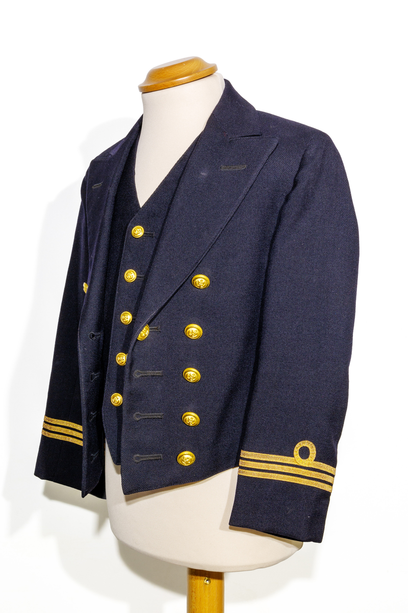 Uniformsjacka (marinen) till barn i mörkblått ylletyg. Försedd med fem rader av guldfärgade knappar med motiv av ankare. Ärmarna pryds av tre rader med guldfärgat band. Jackan är fodrar med ett svart tyg och ett randigt tyg med blå och bruna ränder på oblekt bas på ärmarnas insida. Jackan har en inneficka på höger sida. I jackans nackstycke finns en etikett med texten "Barngarderoben Falun" samt en hängare. 