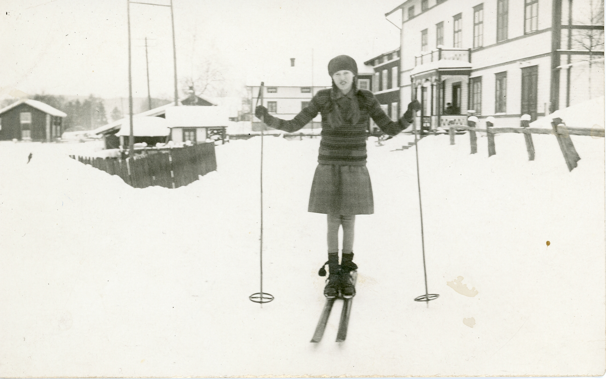 Foto på Linnea Jernberg, Lövstrand (liten by i Vilhelmina kommun), stående på skidor med hus i bakgrunden. 
Texten på baksida fotot- "min fina kompis, hon hade ibland röd-grön randiga strumpor, hon var jättebra".