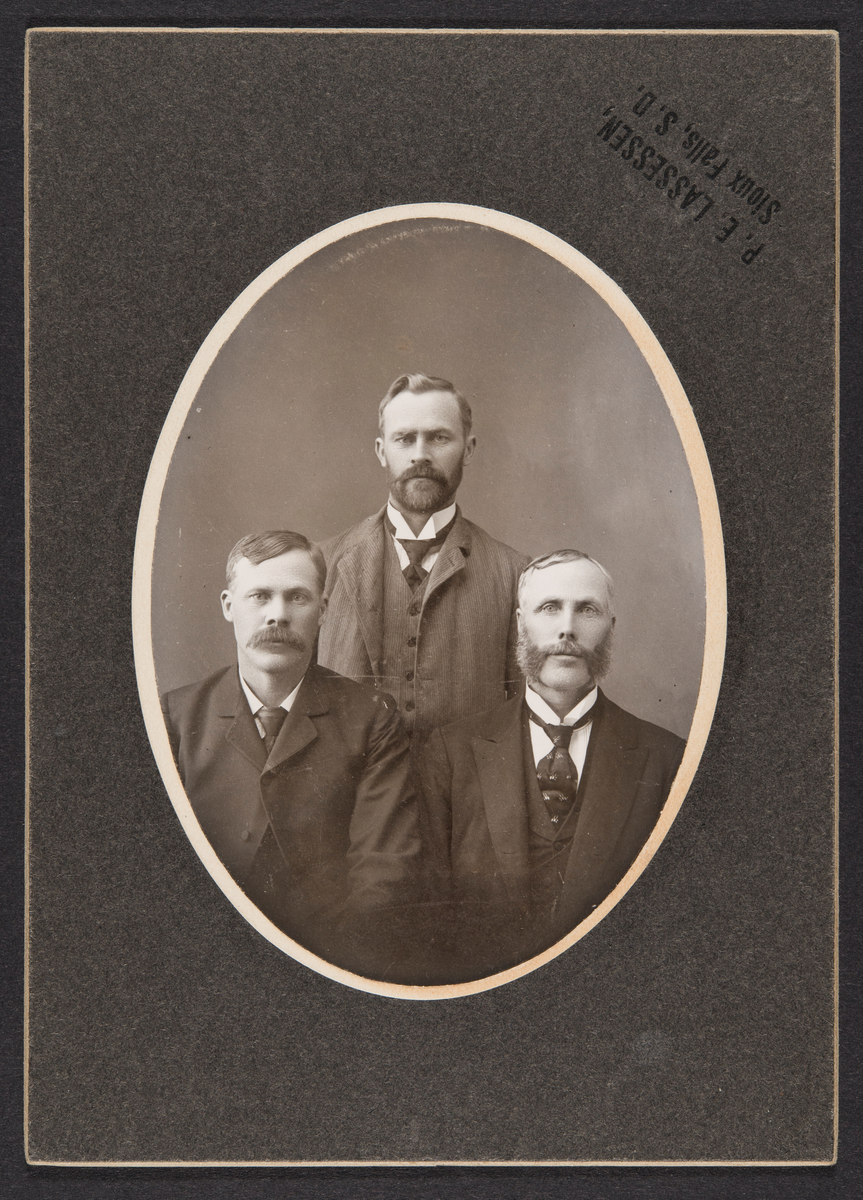 Atelierbilde av tre menn i dress.
Fra venstre mot høyre:
Gustav Gunderson, Yankton, S.D.
Bernt Gunderson, Yankton, S.D.
Thore Gunderson, Beloit, Iowa