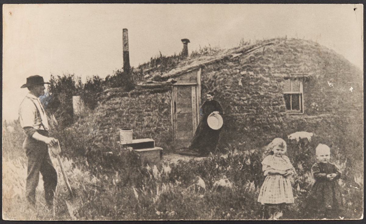 Påskrift: "John Bakkens first house." Milton, Cavalier County, N. Dakota
En familie står foran et torvhus.