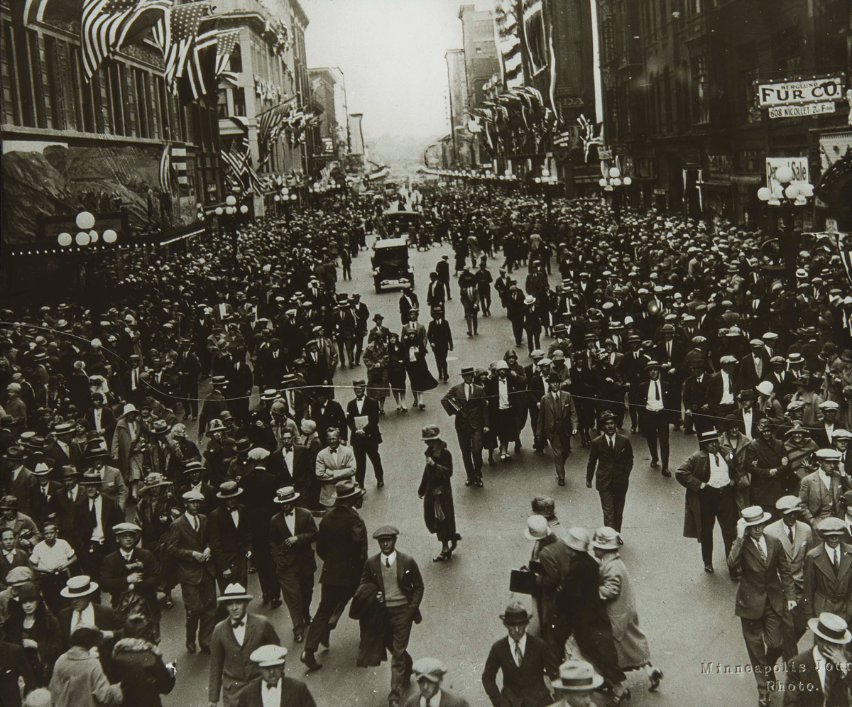 Folkemengde i en flaggpyntet bygate under Innvandrerjubileet i 1925.