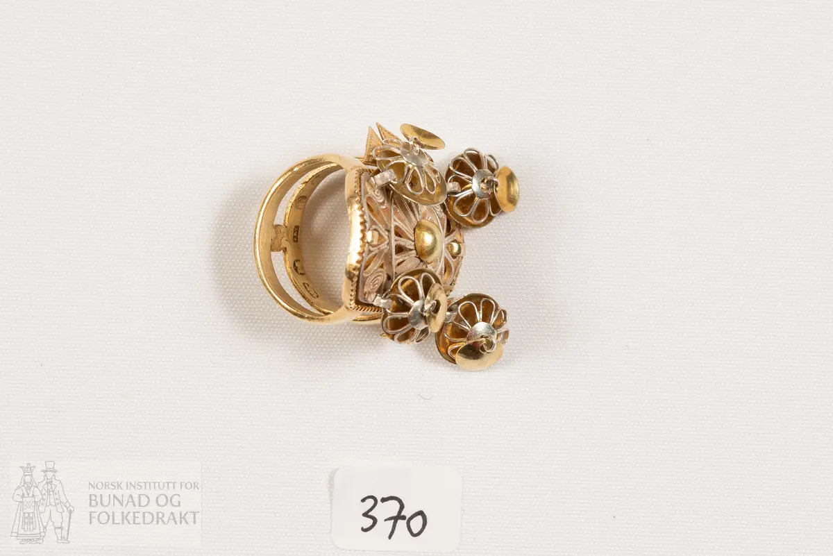 Fingerring. Forgylt sylvring. Dobbel ring med plate dekorert med filigransarbeid. Det same er dei 6 skålene.
Fleire stempel, blant anna 7 prikkar (Bergen bystempel), H.