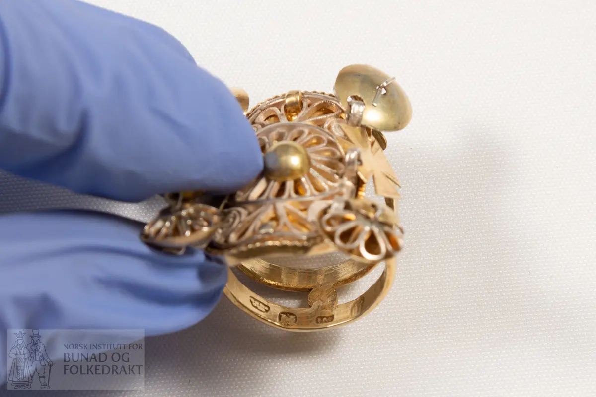 Fingerring. Forgylt sylvring. Dobbel ring med plate dekorert med filigransarbeid. Det same er dei 6 skålene.
Fleire stempel, blant anna 7 prikkar (Bergen bystempel), H.