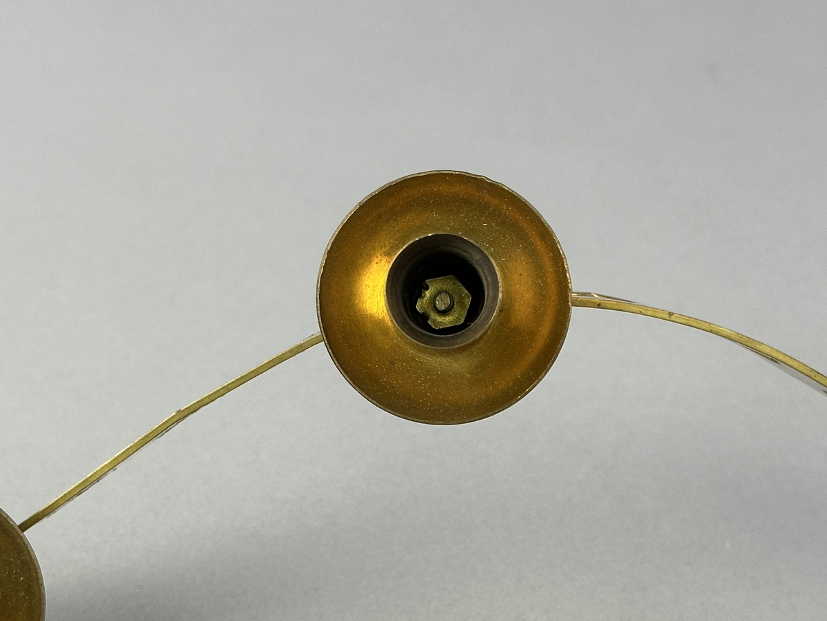 Ljusstake, "Ljusslingan" för sju ljus, består av ett mässingband som böjts i mjuk vågform och dekorerats med stansade stjärnor och hjärtan. Ljushållarna är fastlödda på bandets högkant.