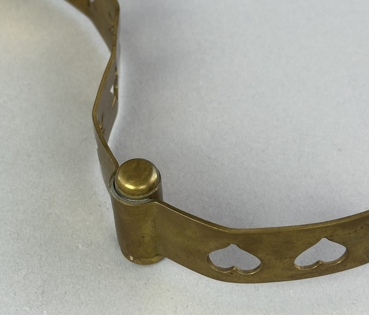 Ljusstake, "Slingan" för fyra ljus, består av ett mässingband som böjts i mjuk vågform och dekorerats med stansade stjärnor och hjärtan i grupper om fem. Mellan dessa grupper sitter ljushållare fastlödda med bandet.